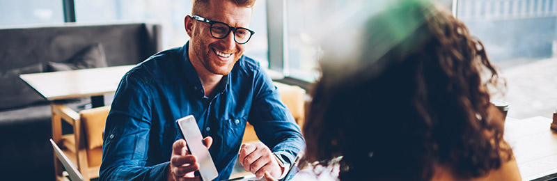 Male entrepreneur showing a female mentor a snapshot of his marketing plan on his phone.