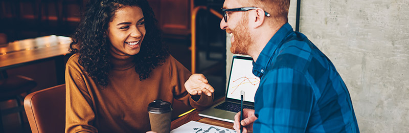 Male and female entrepreneurs reviewing the financials on a laptop for their growth-oriented business plan.
