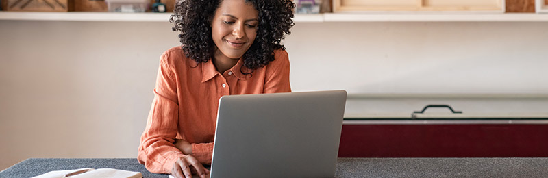 Female entrepreneur working in her home office at the computer on a SWOT analysis to discover the strengths, weaknesses, opportunities, and threats to her business.