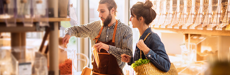 Male entrepreneur helping a female customer find the best spice option in his grocery store. The hand-crafted spices and personalized service are both part of his unique value proposition.