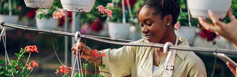 Female entrepreneur working in her flower shop checking on a plant. She's positioning her business as high-end and exclusive thanks to some unique plant varieties.